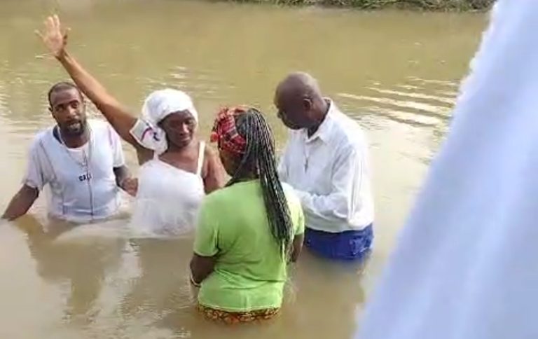 Pastor baptizing a woman, both washed away in river